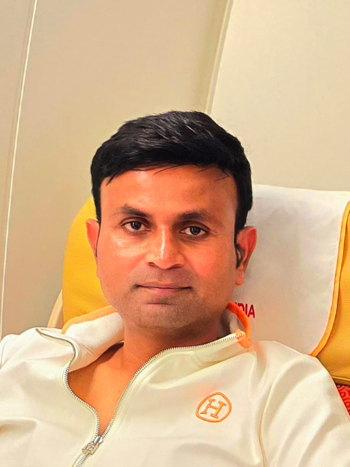 Santosh Davakhar, seated, in a white zip-up jacket.